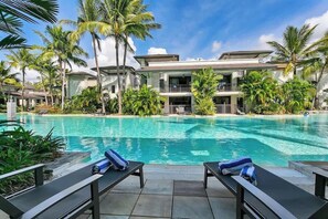 Ein Resort mit Swimmingpool, Liegestühlen und Palmen.