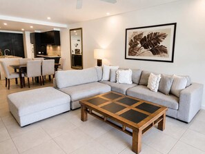 A modern living room with a sectional sofa, a coffee table, and a dining area with chairs.