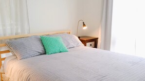 Un lit bien fait, avec une literie à rayures, une tête de lit en bois et une lampe de chevet.