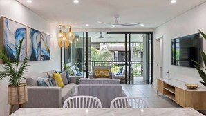 A modern living room with a sofa, dining table, and chairs, a TV, and a balcony with a view. - Rooftop Resort Oasis at Temple with Spa (Craiglie)