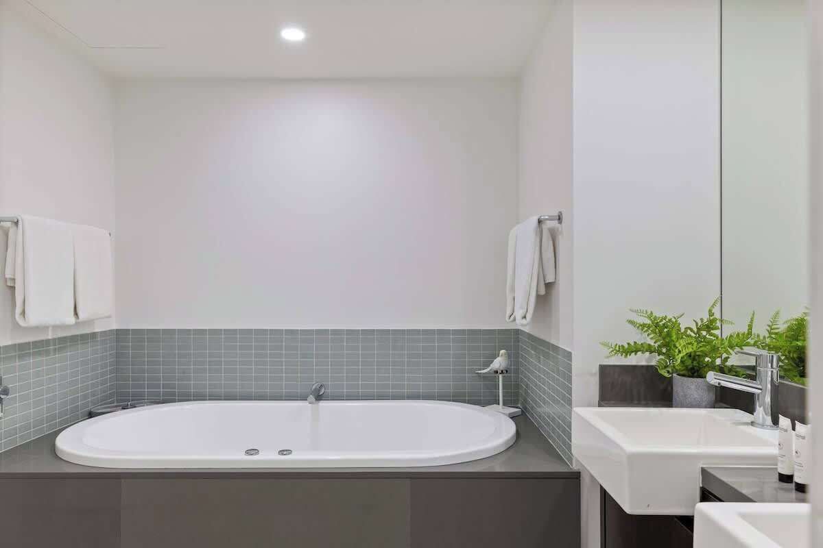 Ein modernes Badezimmer mit einer freistehenden Badewanne, einem Waschbecken und einem Spiegel.