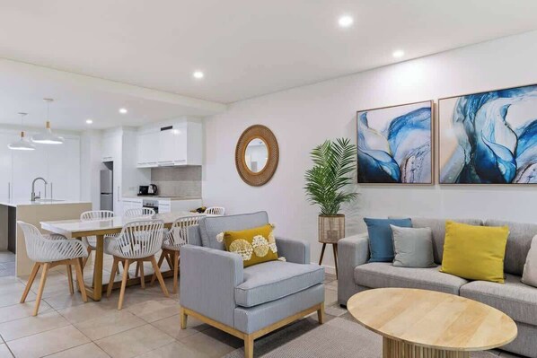 Una sala de estar moderna con sofá, sillón, mesa de comedor y sillas.