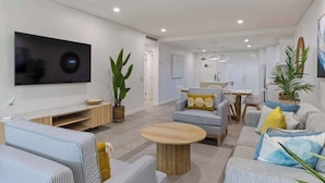 A modern living room with a flat-screen TV, sofas, a coffee table, and a dining area. - Rooftop Resort Oasis at Temple with Spa (Craiglie)