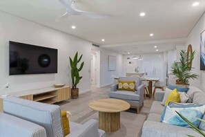 Un salon moderne doté d  ’un téléviseur à écran plat, de canapés, d’une table basse et d’un coin repas.