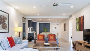 A modern living room with a sofa, coffee table, and TV stand. - Devine Rooftop Penthouse at Temple Resort (Port Douglas)
