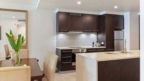 A modern kitchen with dark cabinets, a tiled backsplash, and a central island. - Devine Rooftop Penthouse at Temple Resort (Port Douglas)