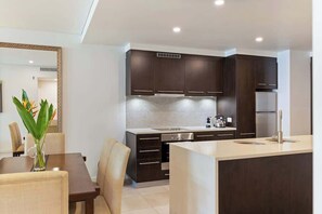 Una cucina moderna con mobili scuri, zoccolo in piastrelle e isola centrale.