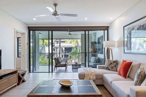Un soggiorno moderno con divano, tavolino e mobile TV. È presente un balcone con mobili da esterno.