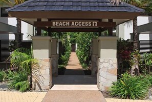 Un ingresso delimitato da cancello con la scritta 'BEACH ACCESS' e un sentiero che conduce a una spiaggia.