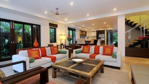 A spacious living area with two white sofas, a coffee table, and a staircase leading to an upper level. - The Villa at Temple: A Luxury Resort Hideaway (Port Douglas)
