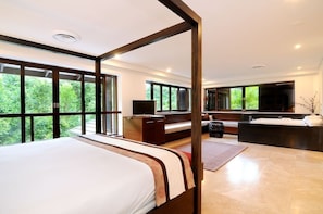 A modern bedroom with a large bed, a desk, a sofa, and a large mirror.