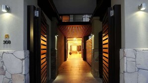 A hallway with a stone wall, a number '308' sign, and wooden slats on the walls. - The Villa at Temple: A Luxury Resort Hideaway (Port Douglas)