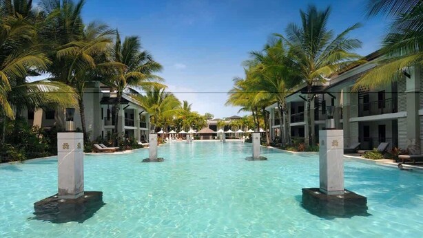 A pool surrounded by palm trees and hotel buildings. - The Villa at Temple: A Luxury Resort Hideaway (Port Douglas)