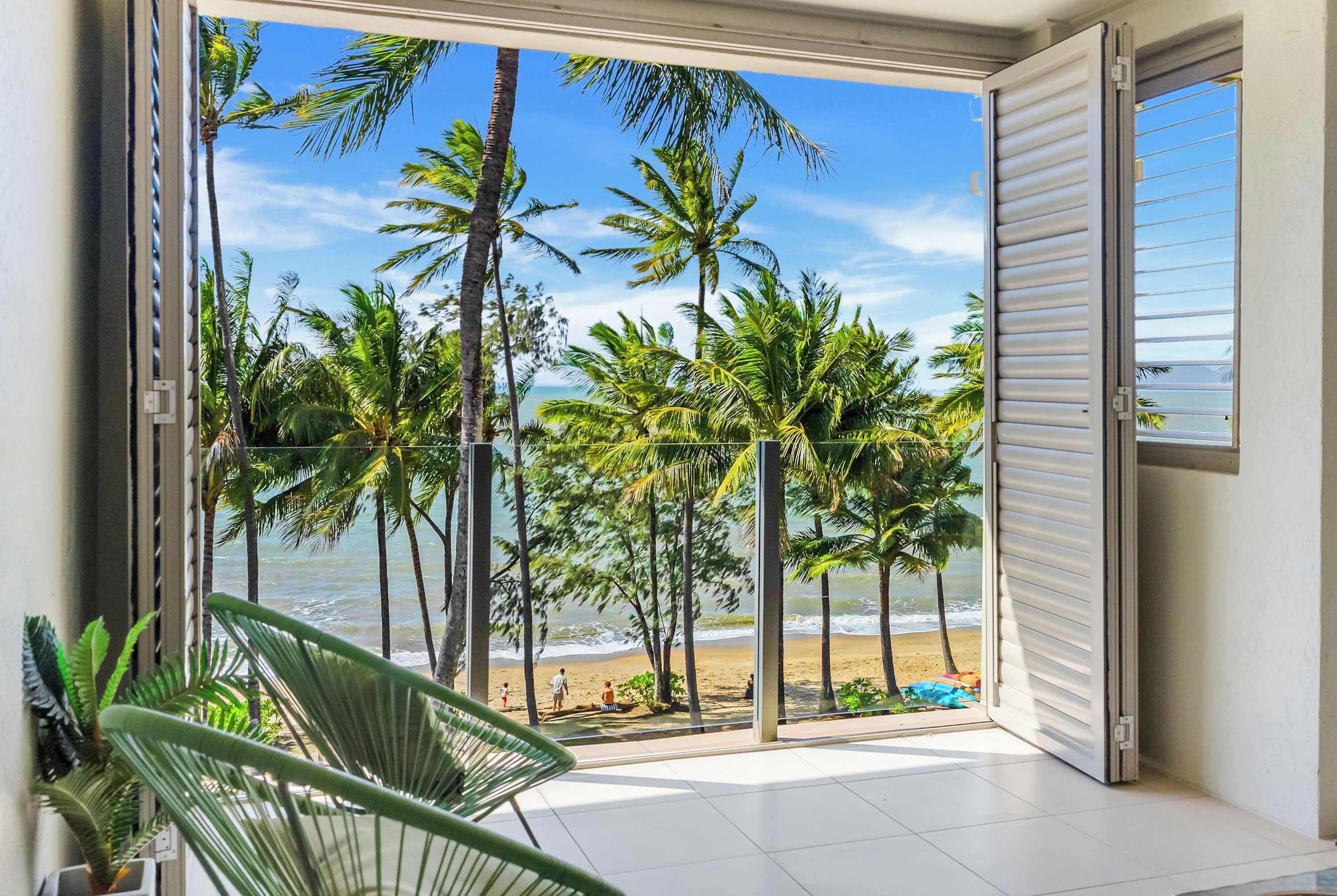 A balcony with a view of a beach and palm trees.