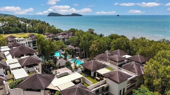A resort with multiple buildings, a swimming pool, and a view of the ocean.