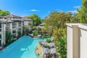 A resort with a swimming pool, multiple balconies, and lush greenery.
