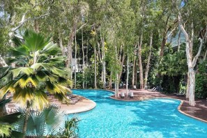Una piscina circondata da alberi e sedie a sdraio.
