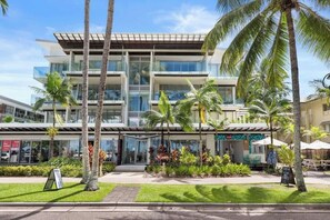Un hotel moderno con facciata in vetro, posti a sedere all'aperto e palme.