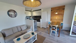 Een moderne woonkamer met een bank, salontafel en een eethoek met stoelen en een houten wand.