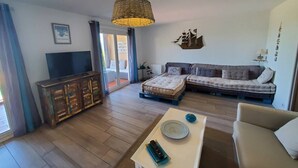 Een woonkamer met een bank, een televisie en een salontafel.