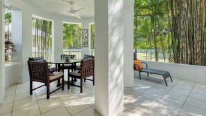Quarto com uma mesa de jantar e cadeiras, um banco, e vista para bambus.