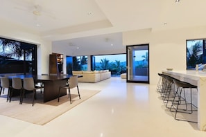 A modern kitchen with a dining area, bar, and a large window with a view.