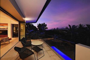 A balcony with a glass railing, a round table, and two chairs.