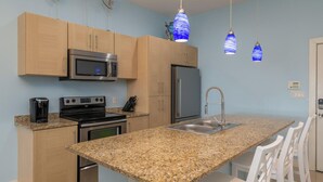 A modern kitchen with granite countertops, stainless steel appliances, and pendant lighting. - Casual Condo Near Beach w/ Pools, hot tub & Grill! (South Padre Island)
