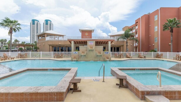 A pool area with two separate pools, a water slide, and a building labeled "LA ISLA" in the background. - Casual Condo Near Beach w/ Pools, hot tub & Grill! (South Padre Island)