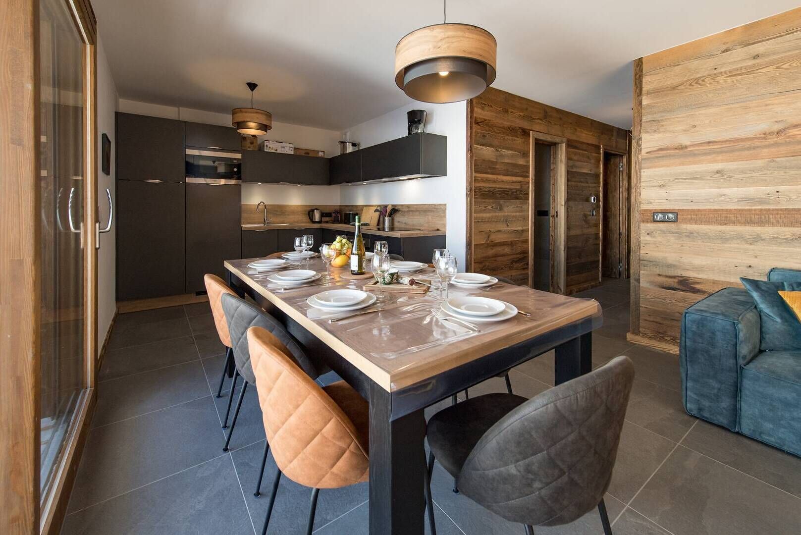 A modern kitchen with dark cabinets, a wooden island, and a dining area with a table set for four.