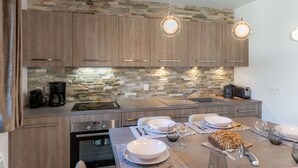 A modern kitchen with a stone backsplash, wooden cabinets, and pendant lighting. - Les 4 ELEMENTS - A11 (CHATEL)