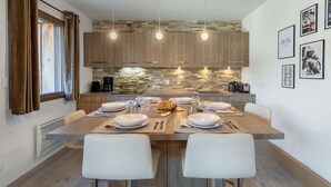A modern kitchen with a central island, pendant lights, and a stone backsplash. - Les 4 ELEMENTS - A11 (CHATEL)