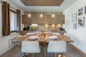 A modern kitchen with a central island, pendant lights, and a stone backsplash.