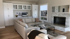 A modern living room with a sectional sofa, a glass coffee table, and a fireplace. - Water view (Mill Valley)