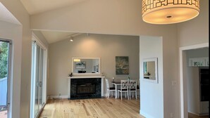 A spacious living room with a fireplace, dining area, and large windows. - Water view (Mill Valley)