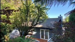 A house with a wooden deck, surrounded by lush greenery and trees. - Water view (Mill Valley)