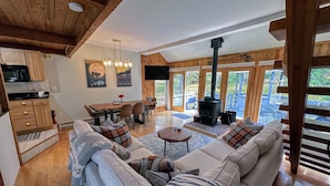 A cozy living room with a sofa, a dining table, and a fireplace. - 43TV peaceful retreat in the White Mountain, fireplace, fire pit, large yard, WiFi, AC! (Twin Mountain)