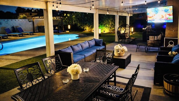 An outdoor patio with a pool, seating areas, and a television screen. - ESCAPE THE MADNESS with no better place to relax!  NEW LUXURY SPA AND HUGE POOL! (North Las Vegas)