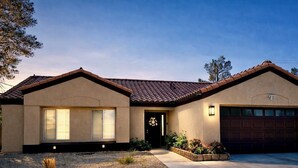 A two-story house with a brown tiled roof, beige stucco exterior, a front door with a decorative wreath, and a garage. - ESCAPE THE MADNESS with no better place to relax!  NEW LUXURY SPA AND HUGE POOL! (North Las Vegas)