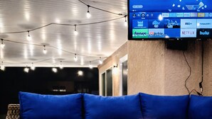 A modern lounge area with a foosball table, blue cushioned seating, and a flat-screen TV displaying various streaming services. - ESCAPE THE MADNESS with no better place to relax!  NEW LUXURY SPA AND HUGE POOL! (North Las Vegas)
