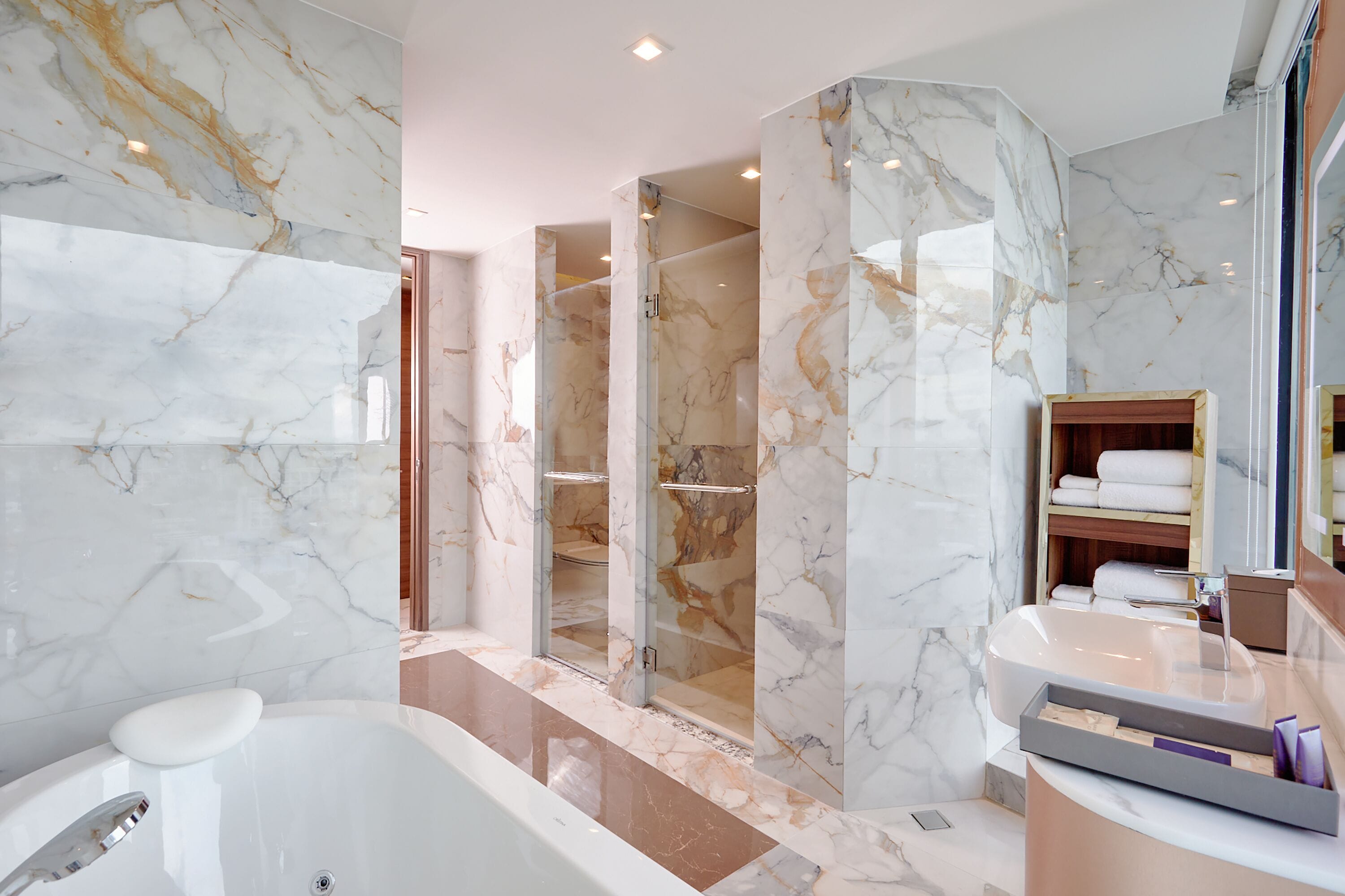 A modern bathroom with a marble vanity, a bathtub, and a shower area.