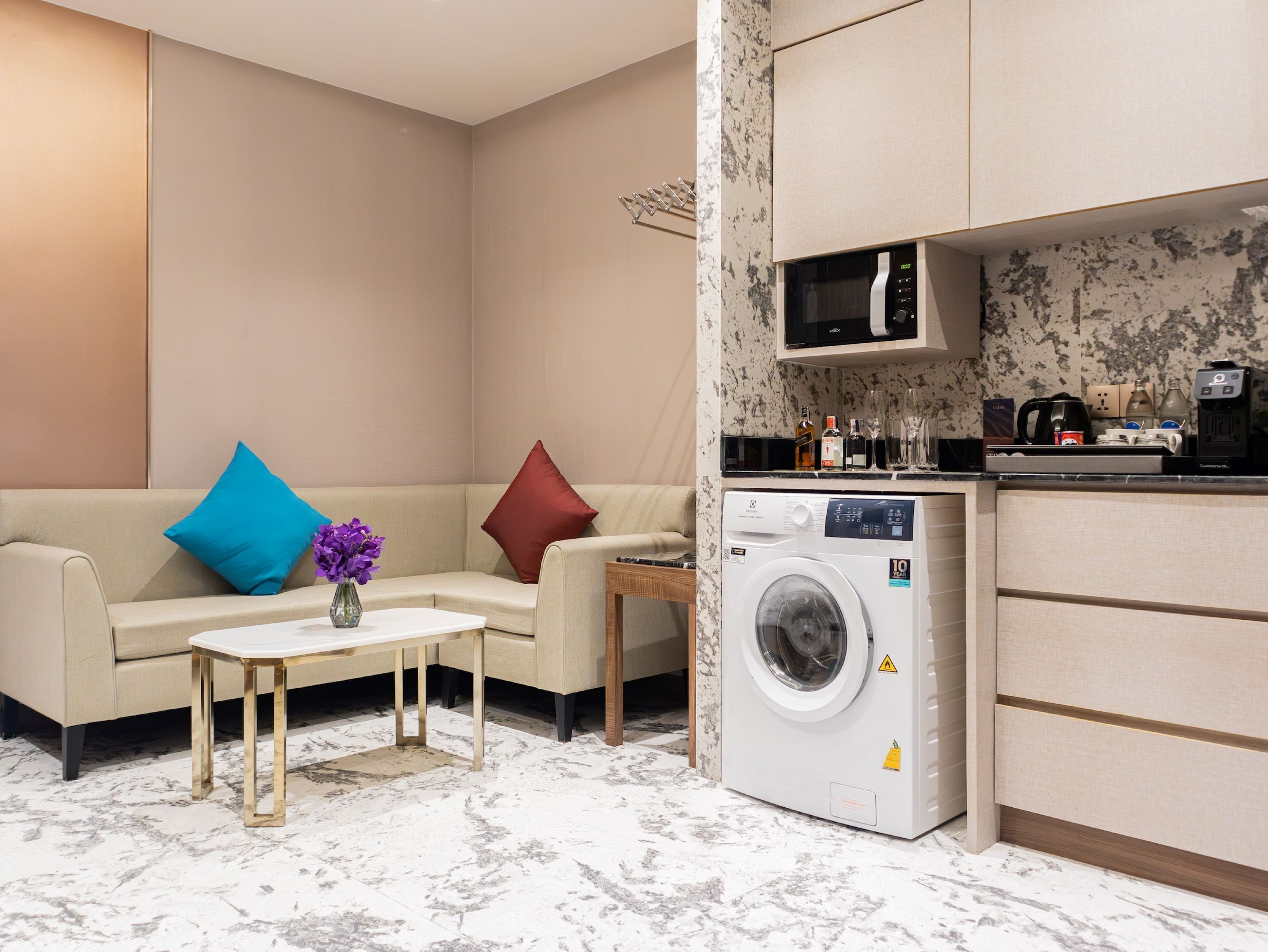 Een moderne woonkamer met een beige bank, een klein bijzettafeltje en een wasmachine.