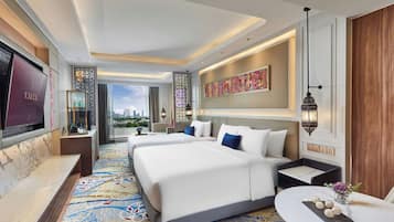 A hotel room with a large bed, a desk with a computer, a TV, and a view of the city.