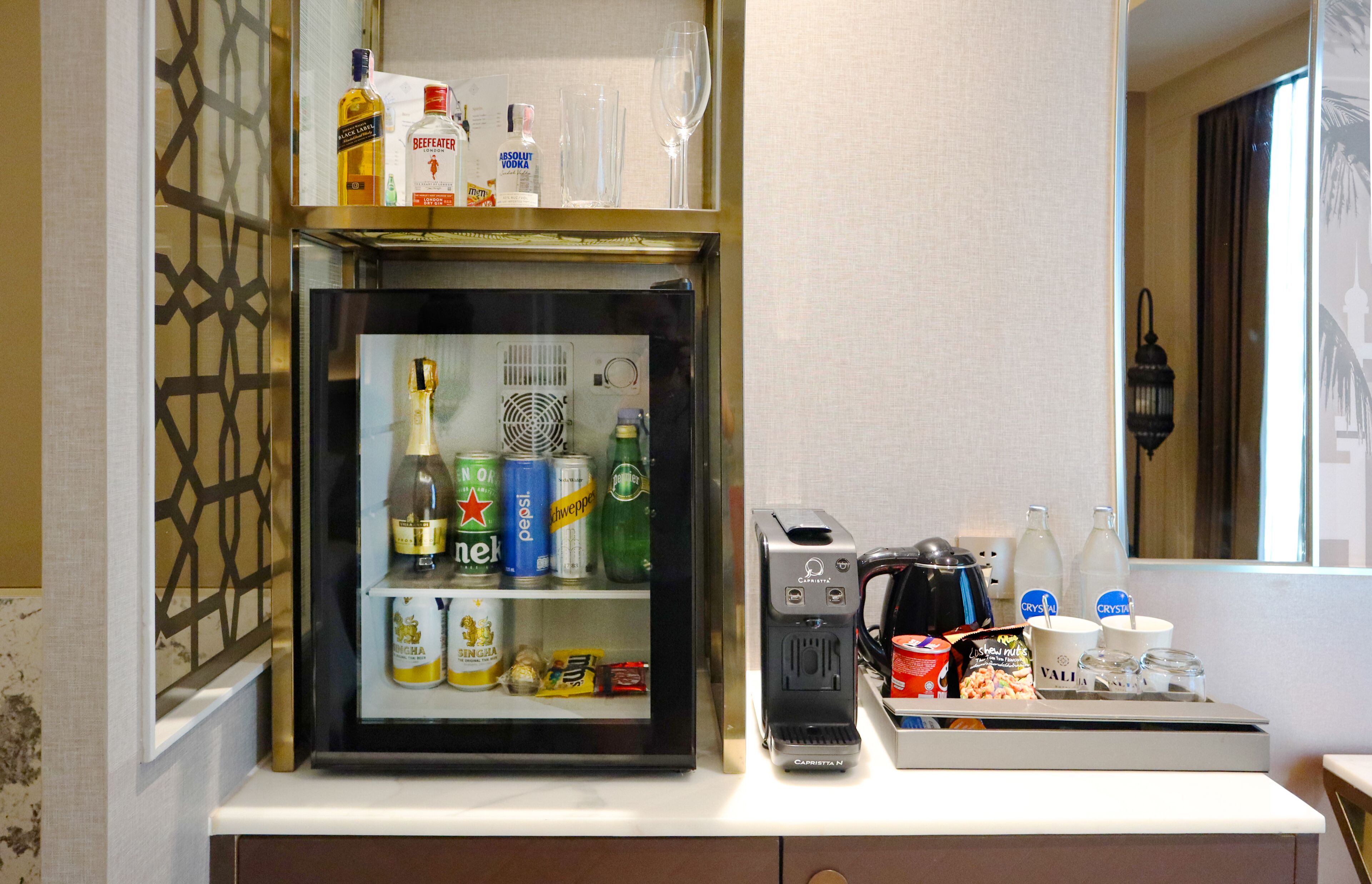 A minibar with a variety of beverages and snacks, a coffee machine, and a small refrigerator.