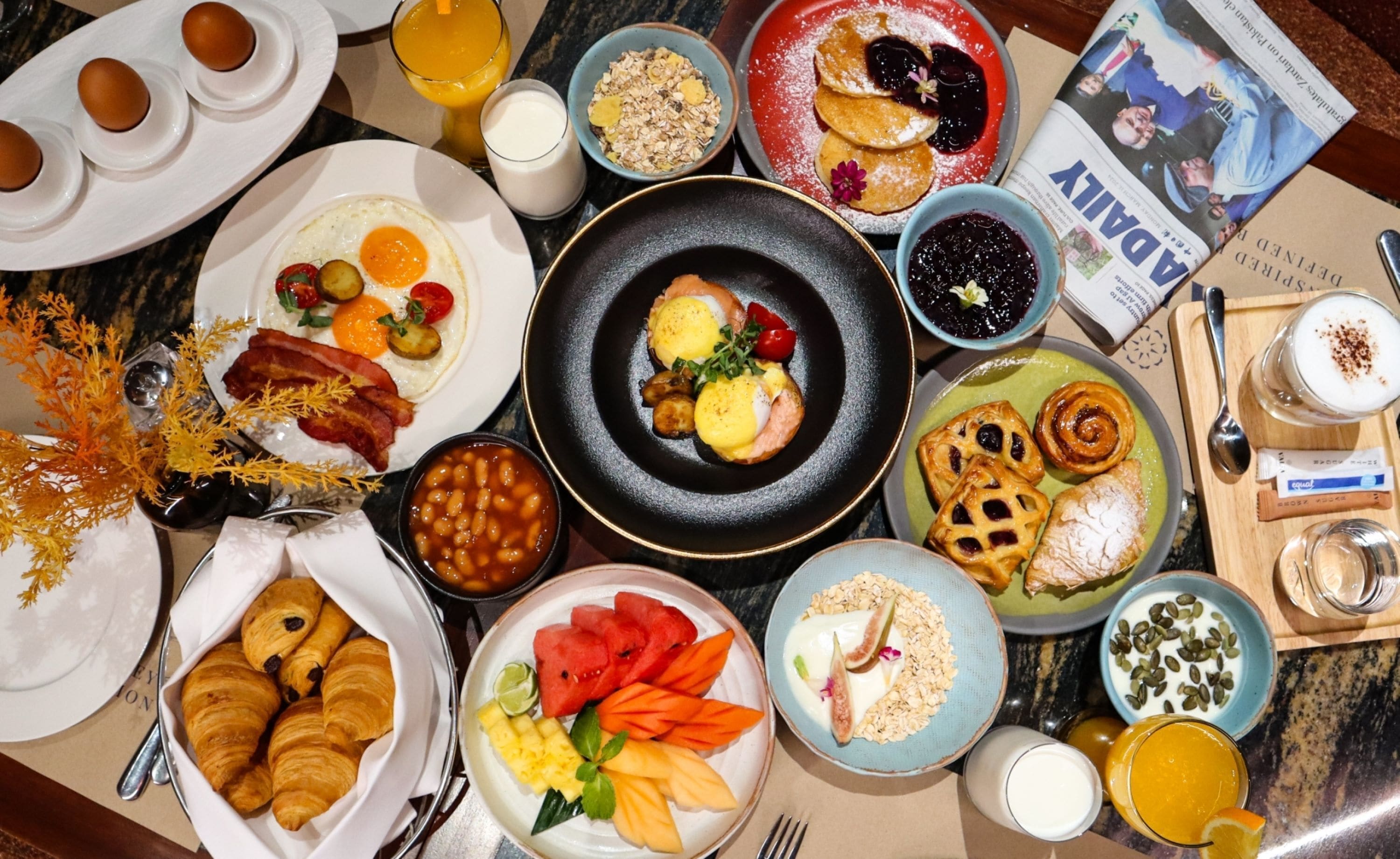 Un bufé de desayuno con diversos platos, incluyendo huevos, pasteles y frutas.
