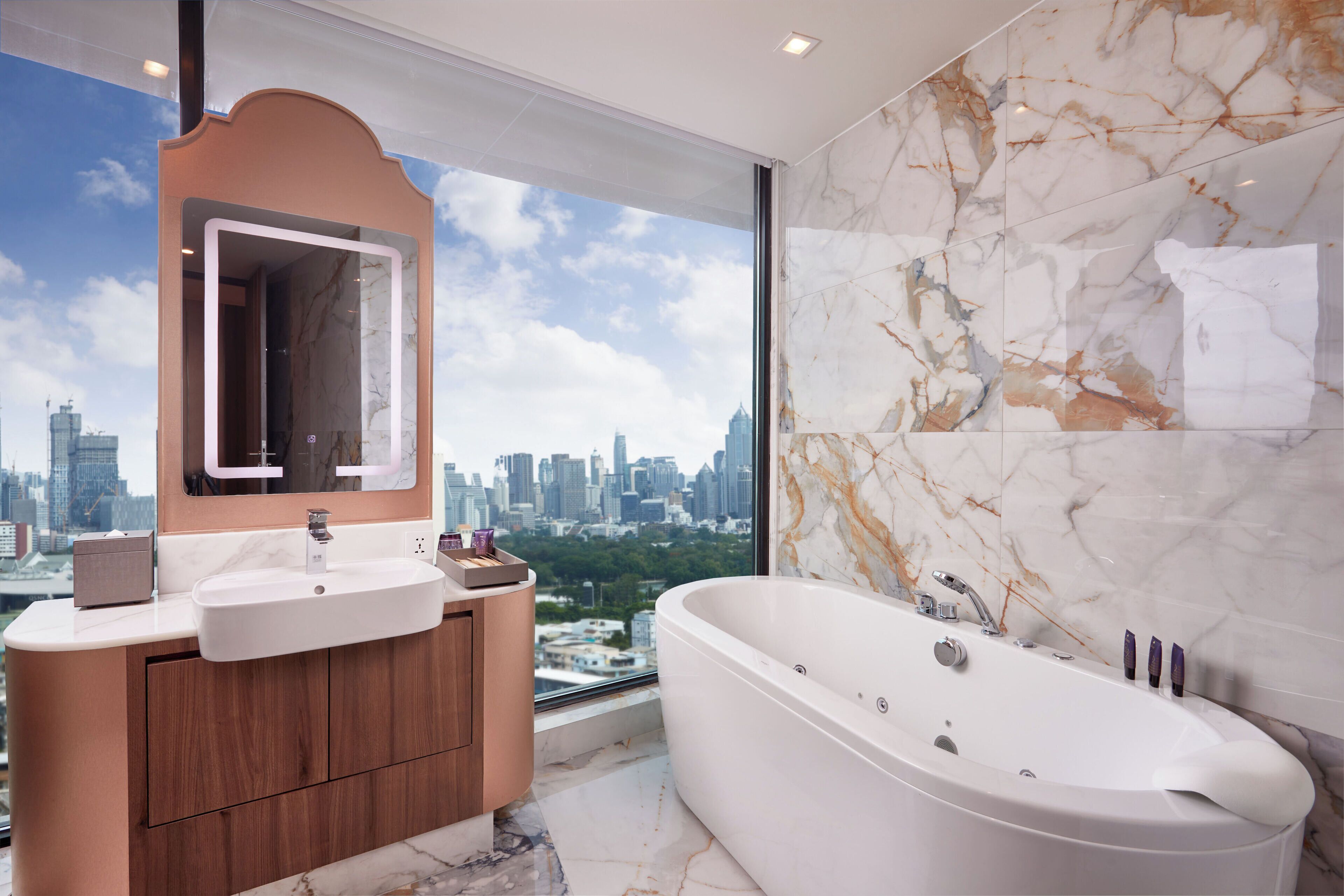 Un baño moderno con vistas a la ciudad, una bañera grande y un tocador con espejo.
