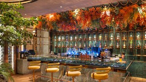 A bar area with a marble countertop, multiple stools, and a decorative wall with hanging plants. - Valia Bangkok Sukhumvit 24 by Kingston Hotels (Bangkok)