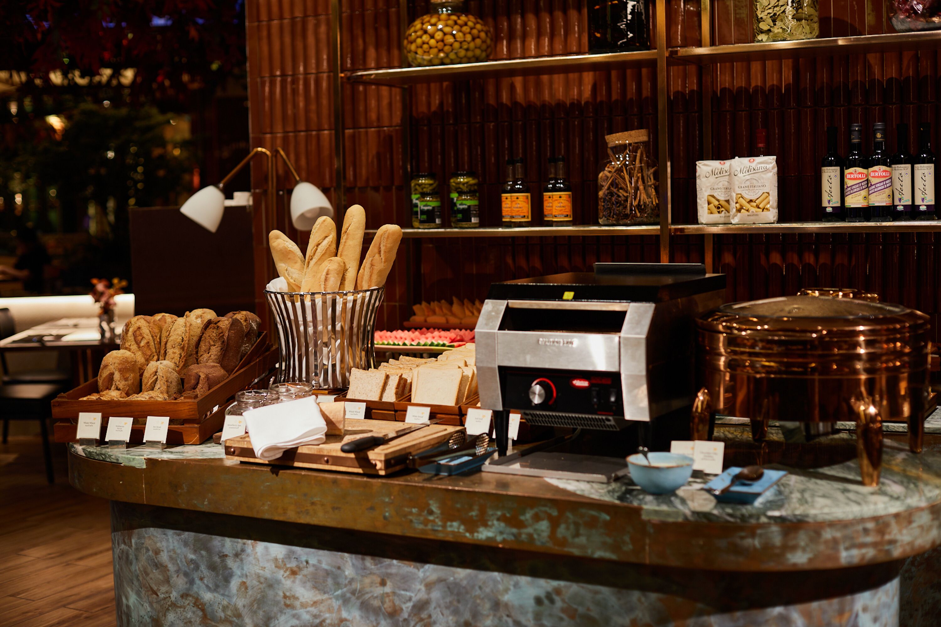 Een bakkerijtoonbank met diverse broden, gebak en toppings.