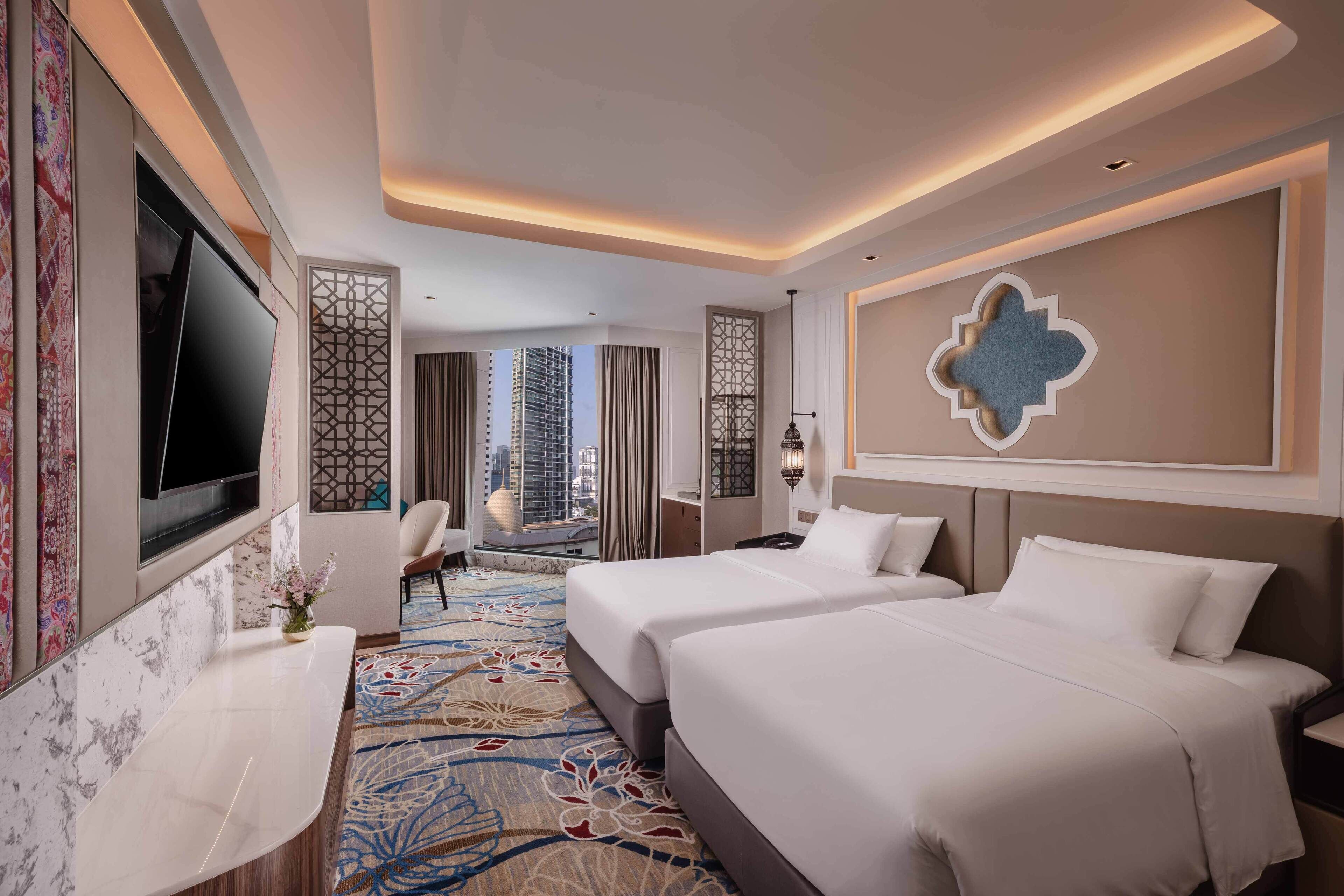 A hotel room with two beds, a TV, a desk, and a decorative wall.