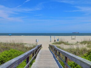 A wooden boardwalk leading to a beach with a ship in the distance. - Wonderful Ocean Views, Heated Pool Access (Tybee Island)
